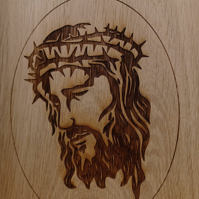 urna per cremazione in legno chiaro con incisa l'immagine di Gesu