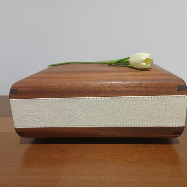 urna per ceneri defunto in legno rivestita da cuoio bianco a cui è appoggiato un tulipano bianco