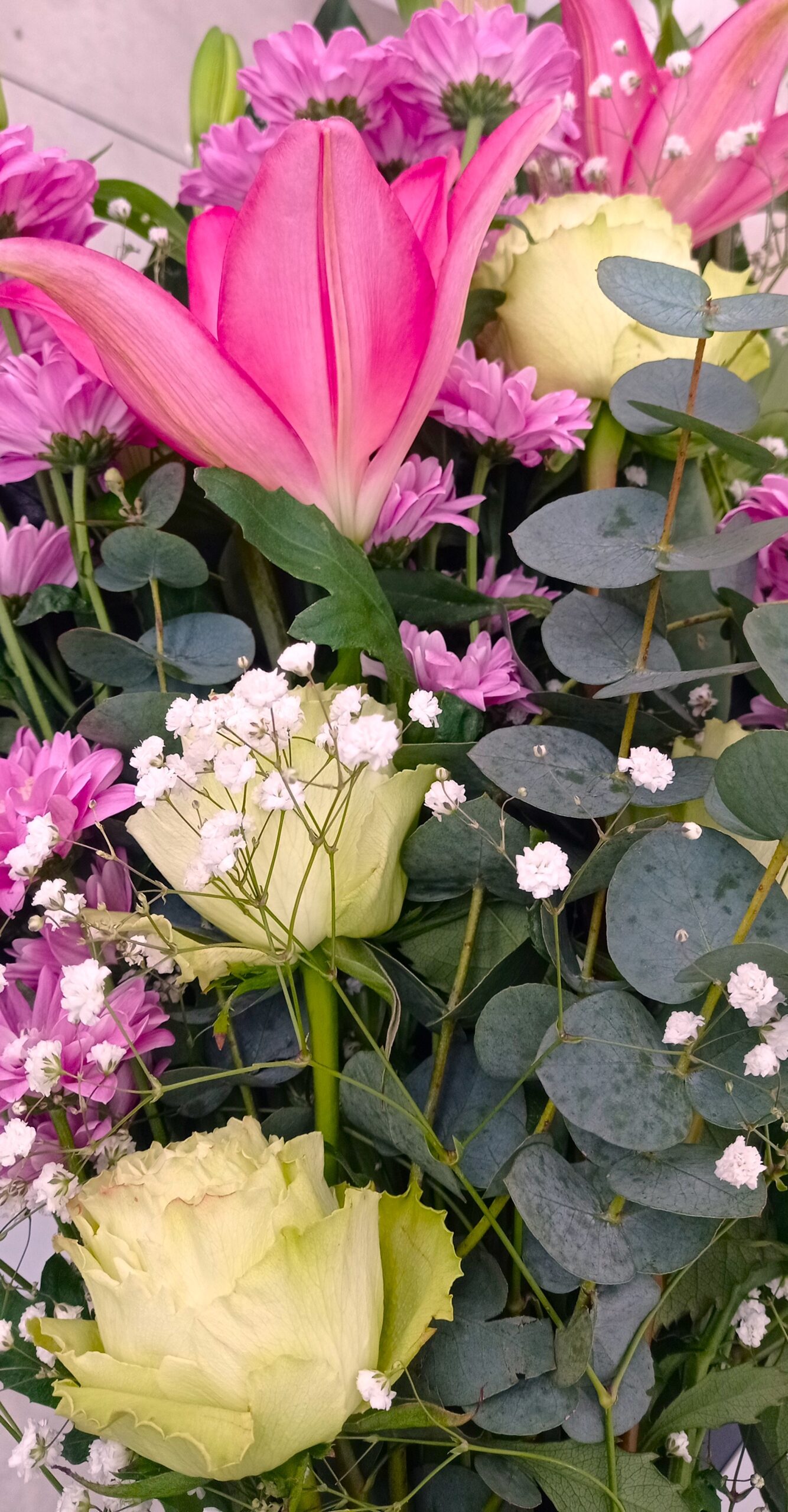 mazzo di fiori formato da rose, ranuncoli e gigli rosa e viola