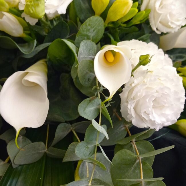 mazzo di fiori bianchi con calle e ranuncoli su una bara