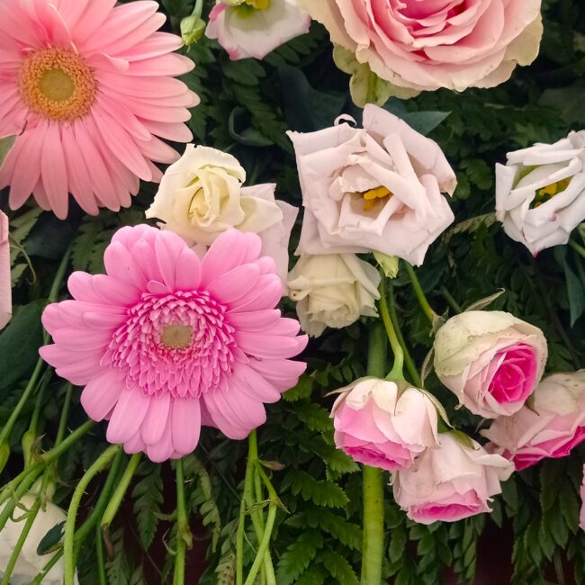 composizione di fiori sui toni del rosa e bianco su una bara