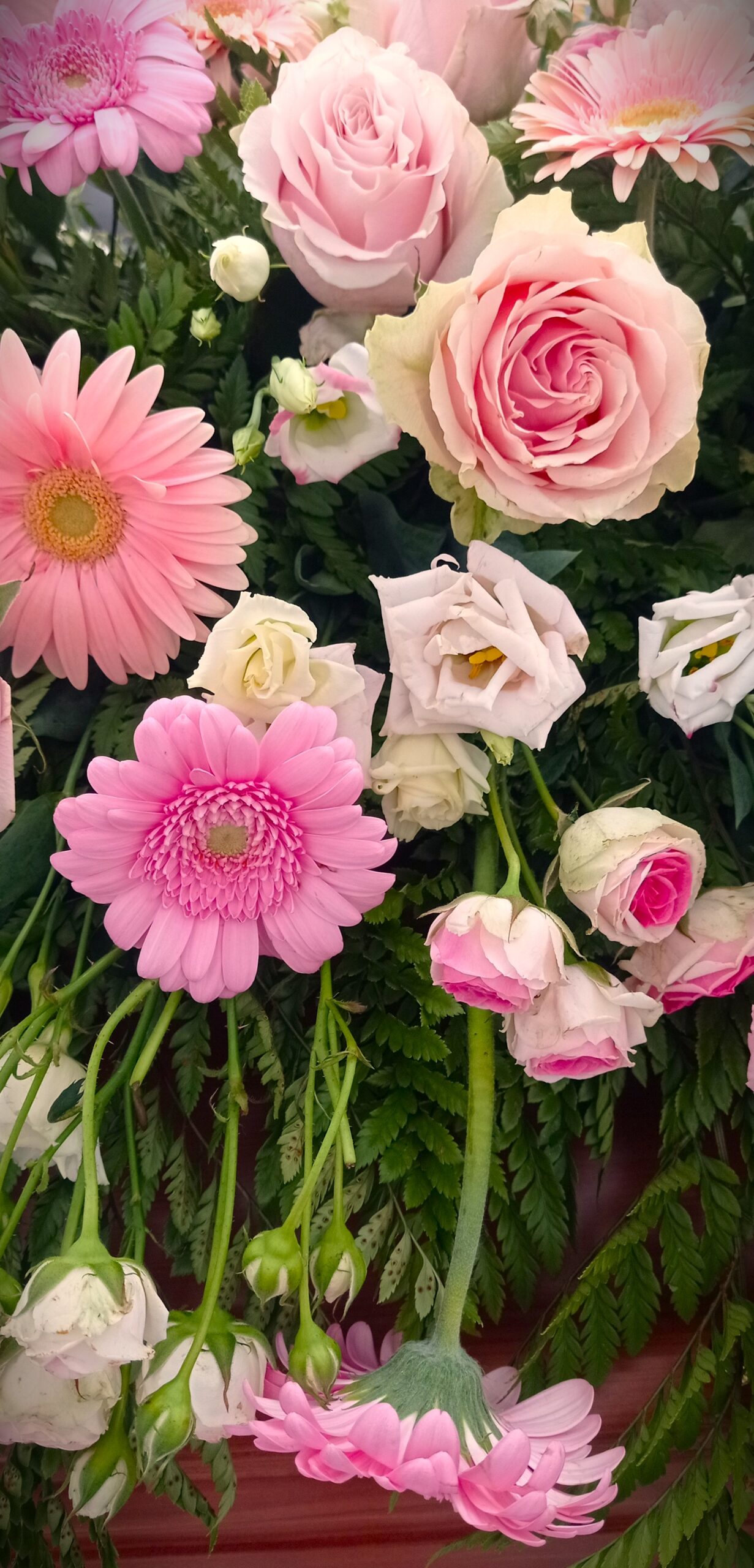 composizione di fiori sui toni del rosa e bianco su una bara