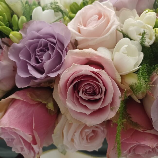 composizione di rose lilla, rosa e bianche per funerale