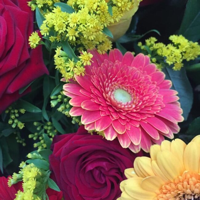 corona funebre composta da fiori rossi e gialli come rose e gerbere