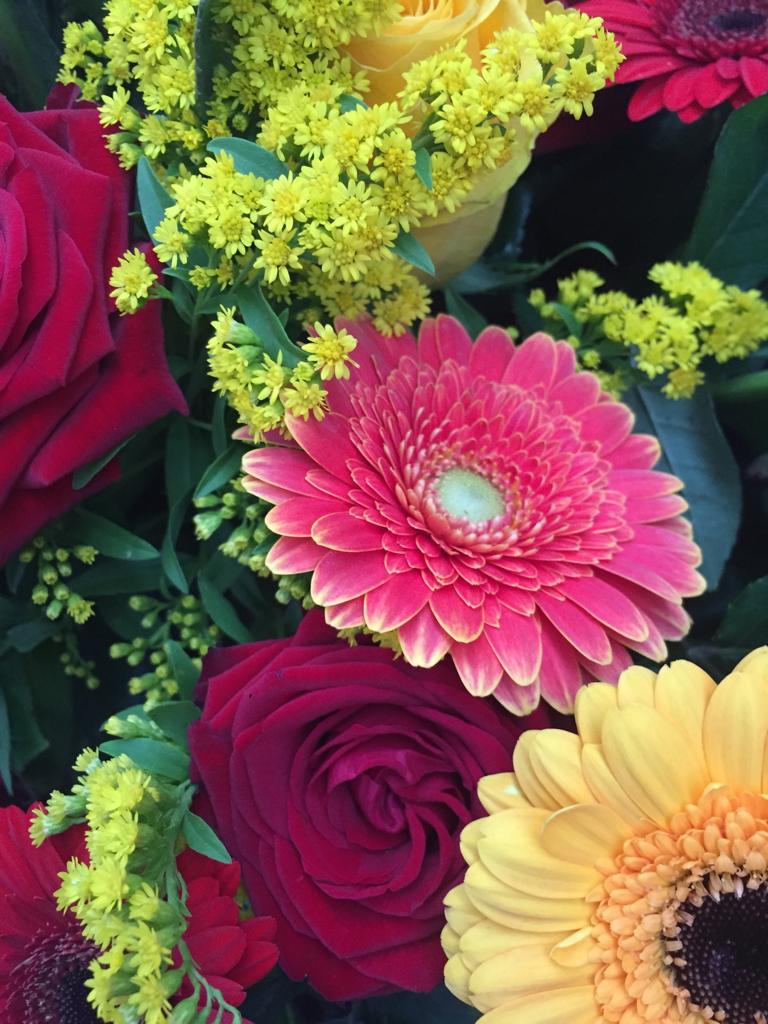 corona funebre composta da fiori rossi e gialli come rose e gerbere