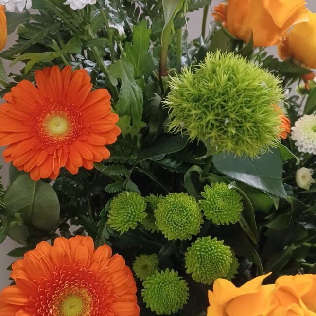 gerbere arancioni e rose gialle con crisantemi in bocciolo e fioriti