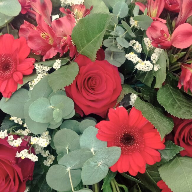 corona di fiori funebre con fiori misti rossi come rose, gerbere e freesia