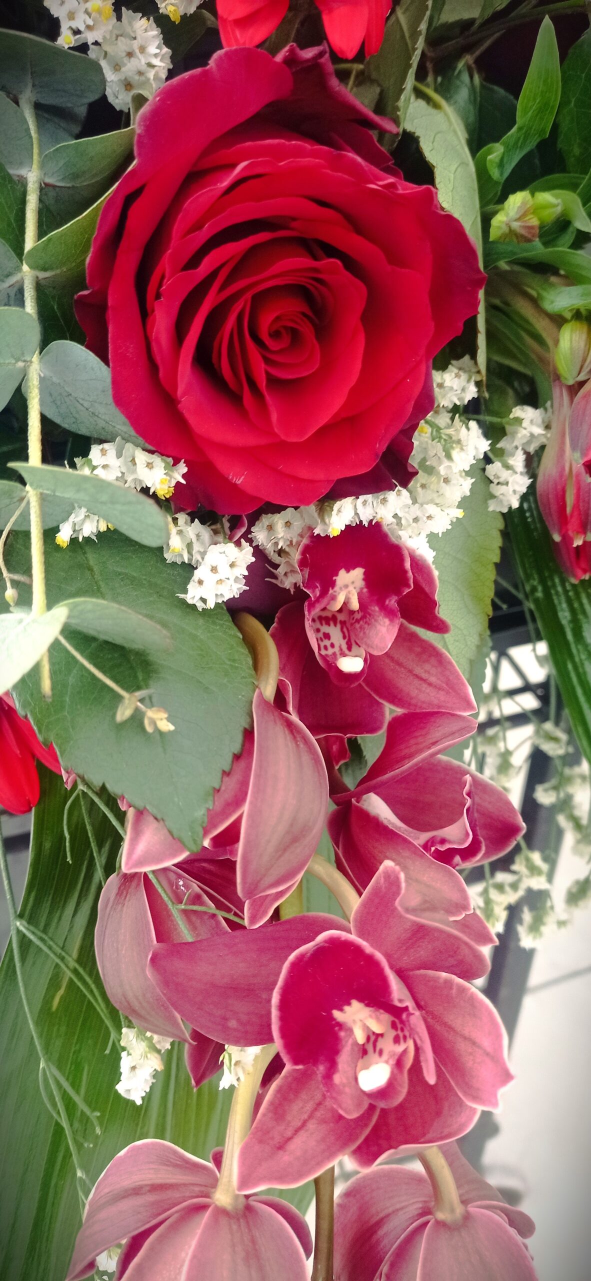 rose e orchidee rosse in una composizione di fiori per funerale