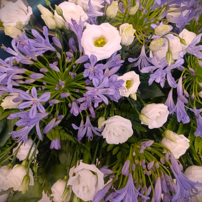 composizione florale funebre roselline bianche e agapanthus viola
