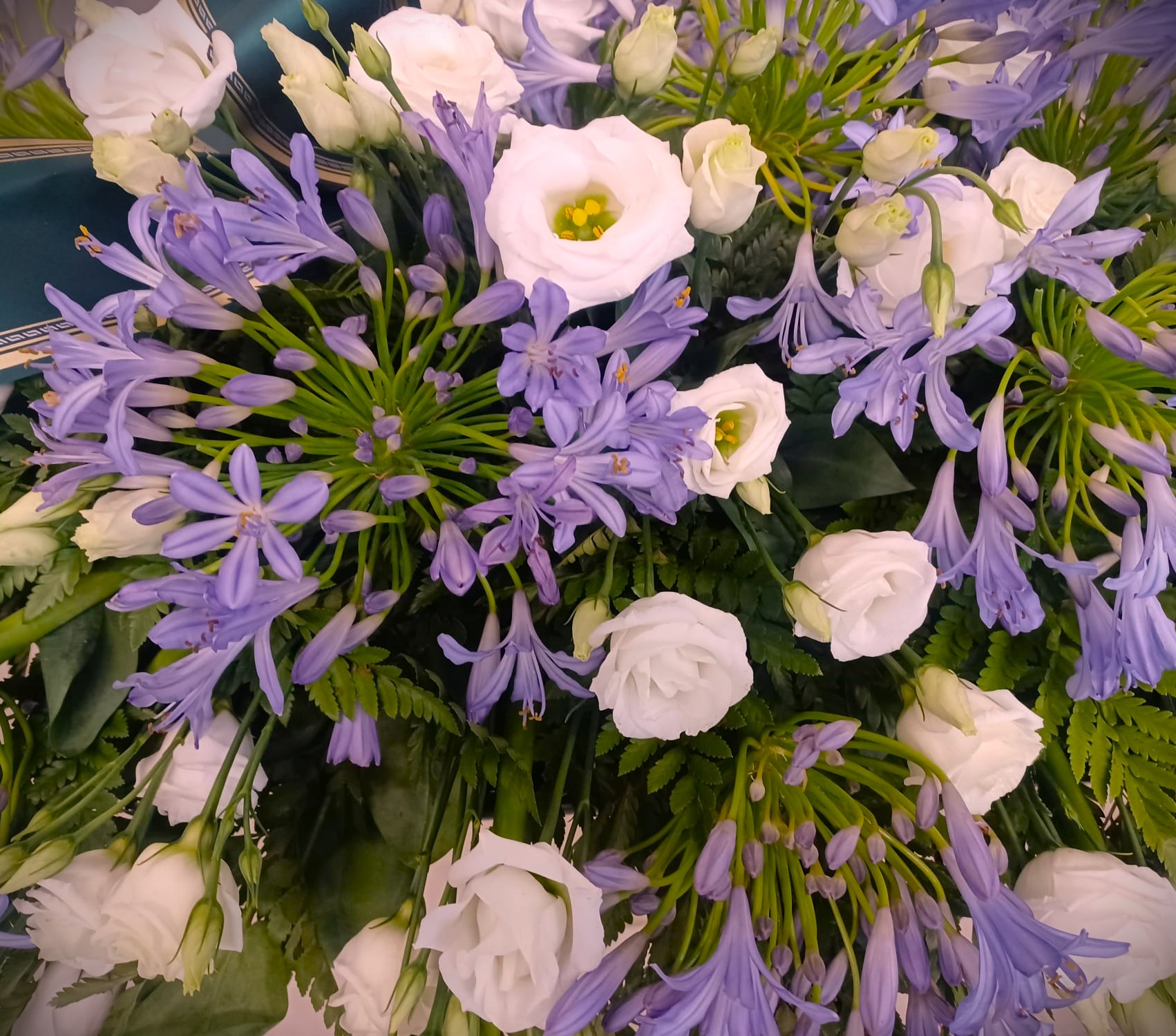 composizione florale funebre roselline bianche e agapanthus viola