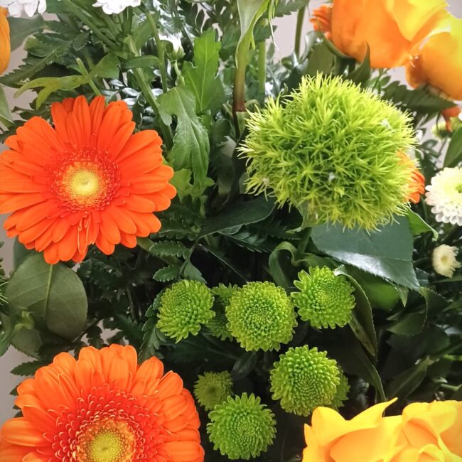 composizione floreale con crisantemi, rose e gerbere di colori arancione e gialli