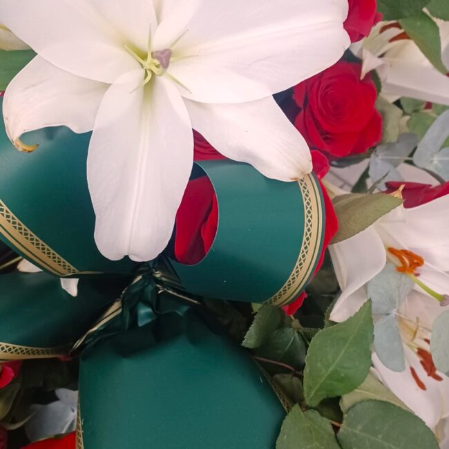 corona di fiori funebre composta da rose rosse e lillium