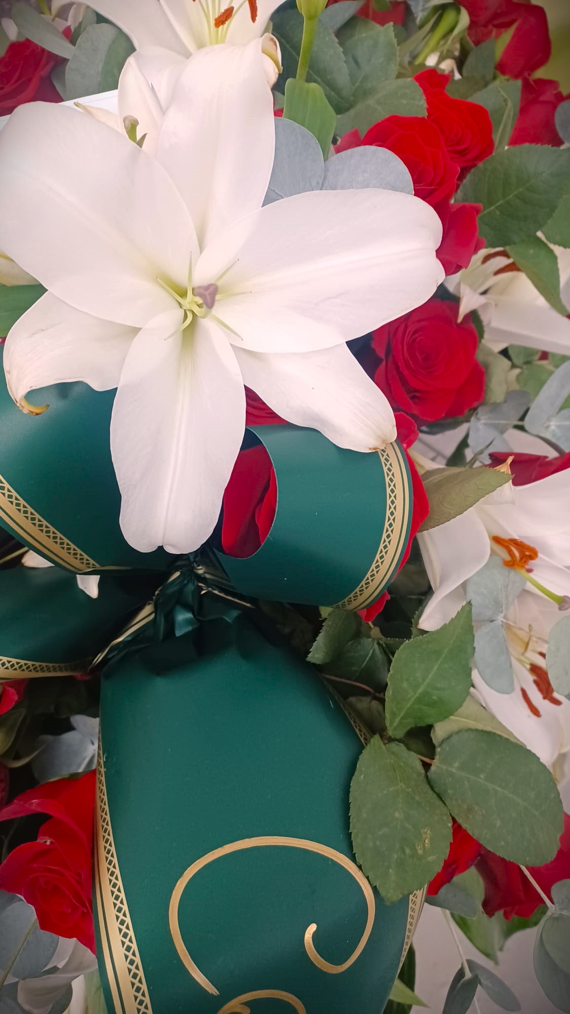 corona di fiori funebre composta da rose rosse e lillium