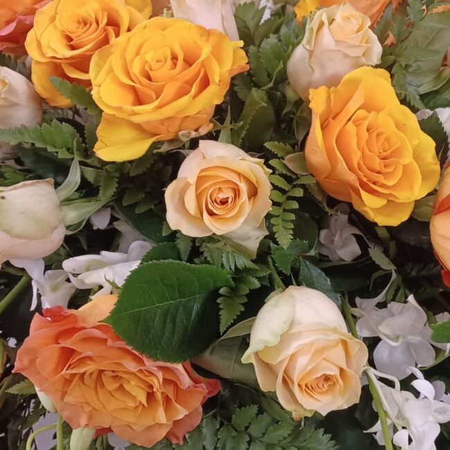composizione florale di rose gialle bianche e arancioni per bara