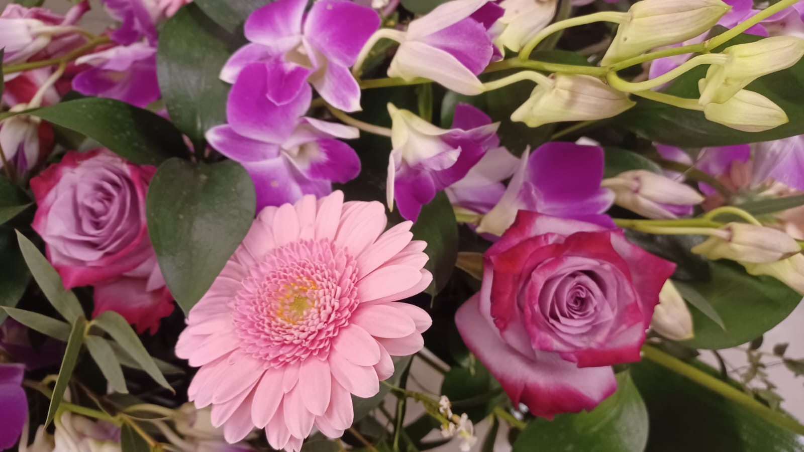 composizione florale mista con rose, orchidee e gerbere rosa e fucsia